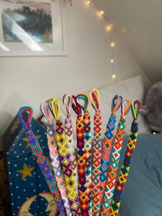 a stack of colorful bracelets sitting on top of a blue box in front of a bed