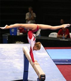 a woman on a balance beam doing a handstand