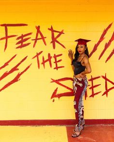 a woman standing in front of a yellow wall with graffiti on it and the words fear the ex