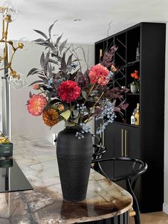 a vase filled with lots of flowers on top of a table next to a black cabinet