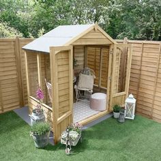 a small wooden shed sitting on top of a lush green field next to a fence