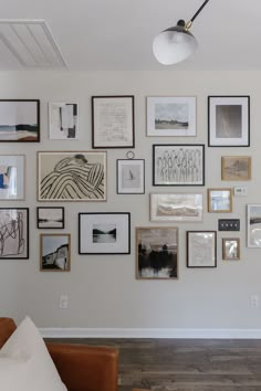 a living room wall filled with lots of framed pictures