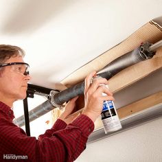 a man is working on an air conditioner in the ceiling with duct tape around his eyes