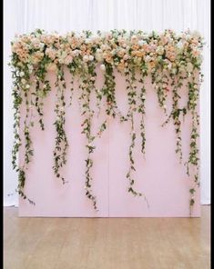 an arrangement of flowers and greenery on a pink wall