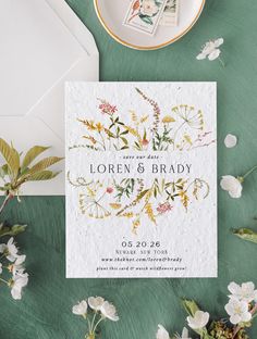 the wedding stationery is surrounded by flowers and greenery