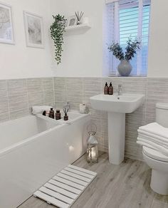 a bathroom with white fixtures and tiled walls, including a bathtub next to a toilet