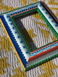 a multicolored photo frame sitting on top of a yellow and white table cloth