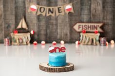 a blue cake sitting on top of a wooden table next to a sign that says one