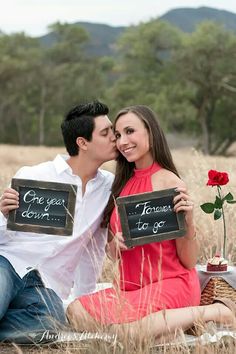 a man and woman sitting on the ground kissing