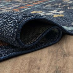 a blue rug on the floor with an area rug that has been rolled up and folded down