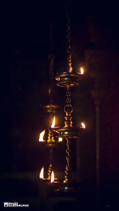 candles are lit in the dark on a chandelier