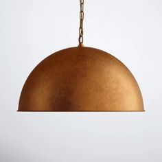 a gold colored pendant light hanging from a chain