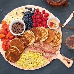 a plate with pancakes, bacon, strawberries, and other breakfast foods on it