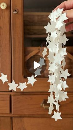 a person is holding some paper stars in front of a wooden cabinet and cupboard door