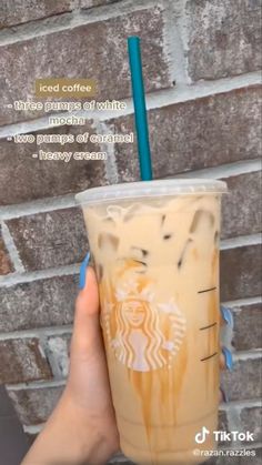 someone holding up a starbucks drink in front of a brick wall with the caption