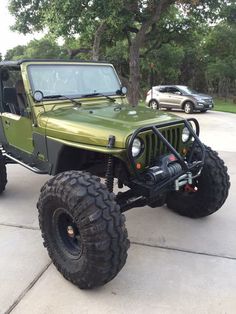 a green jeep parked in front of a tree