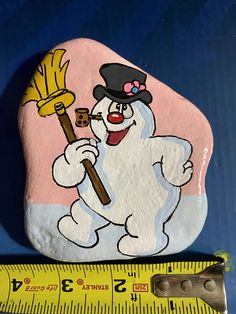 a rock with a cartoon character holding a broom on top of it next to a ruler