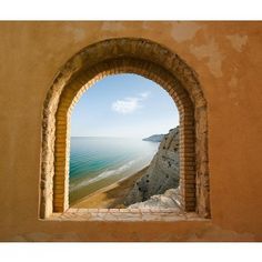 an arched window with a view of the beach and ocean from it's side