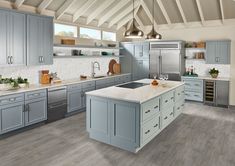 a large kitchen with gray cabinets and white counter tops, stainless steel appliances and an island in the middle