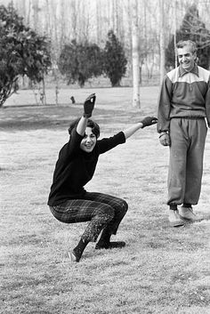 an old black and white photo of two people playing frisbee in the park