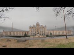 an old building with trees and grass in front of it on a foggy day