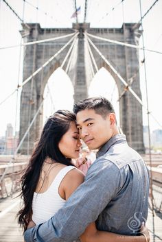 a man and woman standing next to each other in front of a bridge with the brooklyn bridge in the background