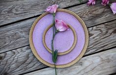 two plates with flowers on them sitting on a wooden table next to some pink flowers