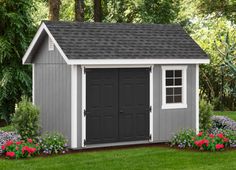 a gray and white shed with flowers around it