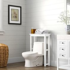 a white toilet sitting in a bathroom next to a wooden table and sink under a mirror