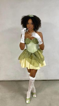 a woman in a green and yellow dress with white gloves on her head is posing for the camera