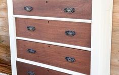 an old dresser is painted white and brown with wood grain on the bottom, along with metal knobs