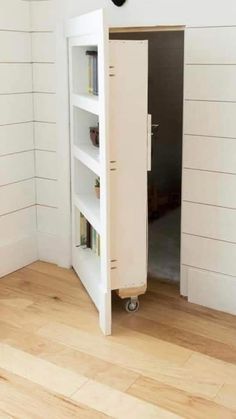 an open book shelf in the corner of a room with white walls and wood floors