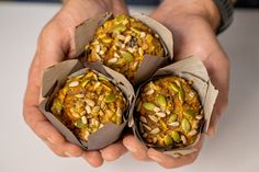 three muffins with nuts and seeds in their hands