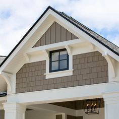 the front entrance to a house with white trim and brown shingles on the roof