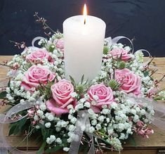 a bouquet of pink roses and white baby's breath with a lit candle