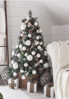 a christmas tree with white and silver ornaments in a room next to a ladder bed