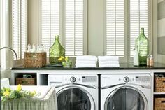 a washer and dryer in a room with white shutters on the windows