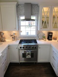 a stove top oven sitting inside of a kitchen next to white cupboards and drawers