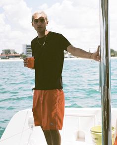 a man standing on the front of a boat holding a cup