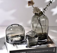 two glass vases with flowers in them on top of a book