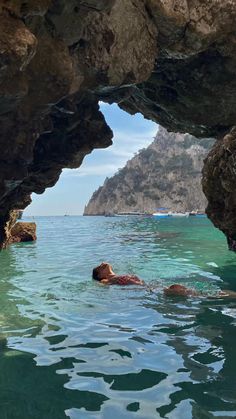 a person swimming in the ocean near some rocks