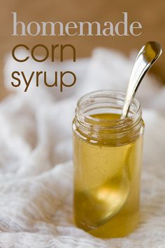 a jar filled with honey sitting on top of a white blanket next to a spoon