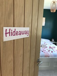 a bed room with a neatly made bed and a sign on the door that says hideaway