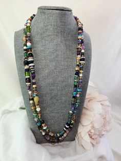 This is my Rhapsody Necklace, a 58" long, one-of-a-kind necklace made from thousands of different beads from around the world. Many of the beads are from a broken piece of jewelry that I will never be able to repair or replace so they're kind of special. Glass, ceramic, crystal, semi-precious stones and crystals, metal beads, pearls, wooden beads, and more come together in a long, kaleidoscope confetti rope of colors that cannot be duplicated. The Rhapsody Multichain Necklace is 51" long and can be worn in many different ways for many different occasions and look stunning every time. This item ships free to any address in continental USA. Beaded Long Necklace Gems And Cabochons For Jewelry Making, Spiritual Beaded Lariat Long Necklace, Long Gemstone Beads Necklace, Bohemian Double Strand Beaded Necklaces With Polished Beads, Bohemian Double Strand Polished Beads, Bohemian Double Strand Polished Beaded Necklaces, Artisan Multi-strand Faceted Beads, Unique Multi-strand Gemstone Beads, Unique Lariat Beaded Necklace With Gemstone Beads