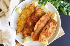 fried fish with lemon wedges and parsley garnish on a white plate