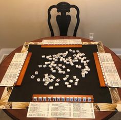 a wooden table topped with lots of dominos on top of a black cloth covered table