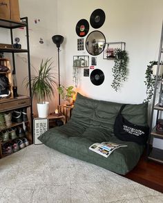 a living room filled with lots of furniture and plants on the wall above it is a green futon sofa