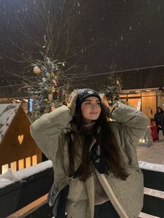 a woman standing in the snow with her hands on her head and arms behind her head