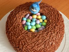 a cake with chocolate frosting and candy eggs in the shape of a bird's nest