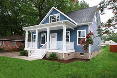 a small blue house with white porch and stairs